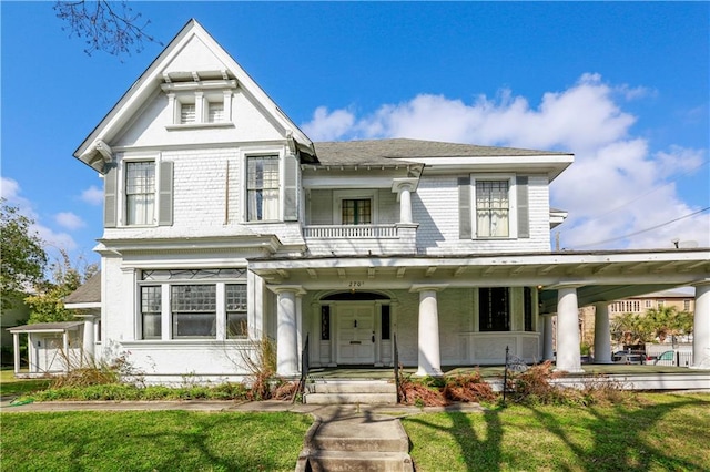 victorian-style house featuring a front lawn and covered porch