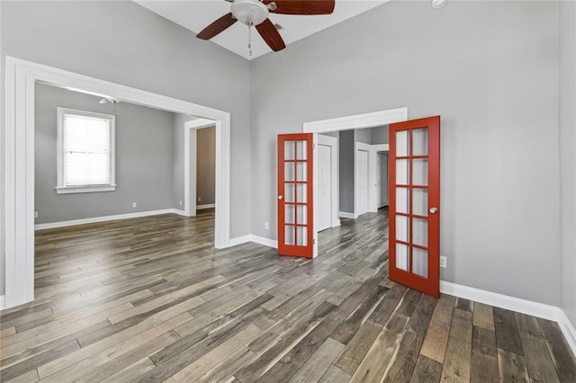 unfurnished room featuring a towering ceiling, french doors, hardwood / wood-style floors, and ceiling fan