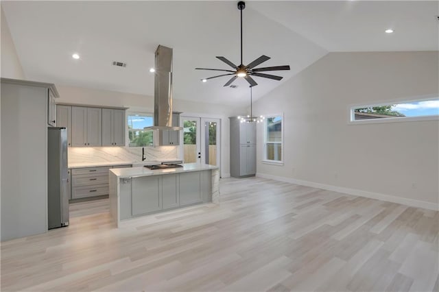 kitchen featuring light wood-type flooring, a center island, tasteful backsplash, and gray cabinets