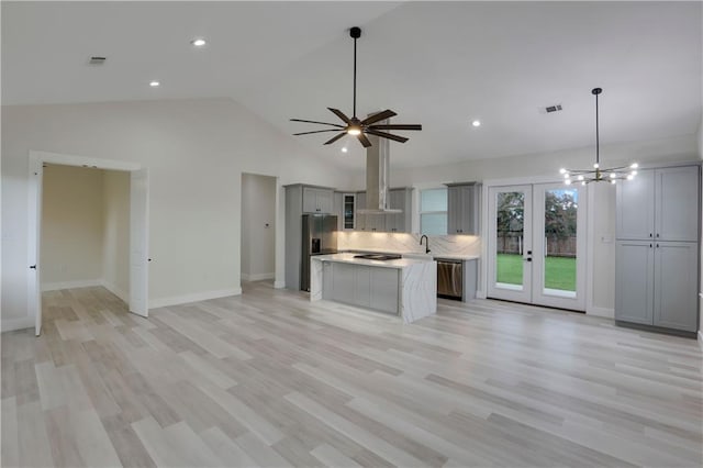 kitchen featuring stainless steel appliances, gray cabinetry, backsplash, french doors, and a kitchen island