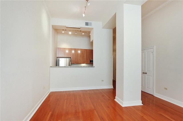 unfurnished living room featuring rail lighting and light wood-type flooring