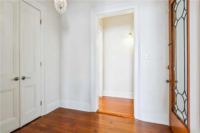 hall with dark wood-type flooring and a chandelier