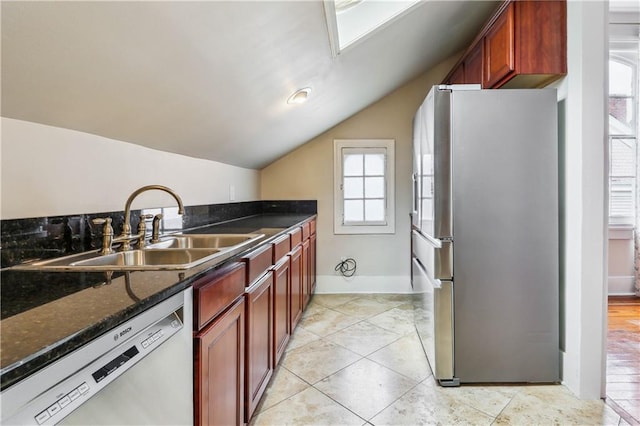 kitchen featuring dark stone counters, appliances with stainless steel finishes, sink, and lofted ceiling