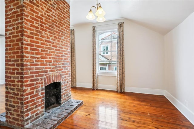 unfurnished living room with a brick fireplace, light hardwood / wood-style floors, lofted ceiling, and a notable chandelier