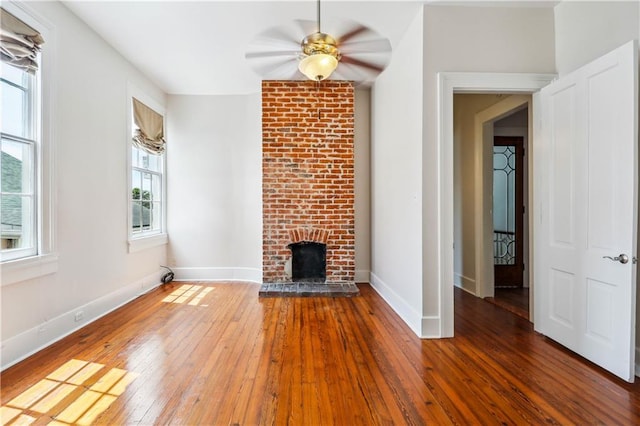 unfurnished living room featuring ceiling fan, wood-type flooring, and a fireplace