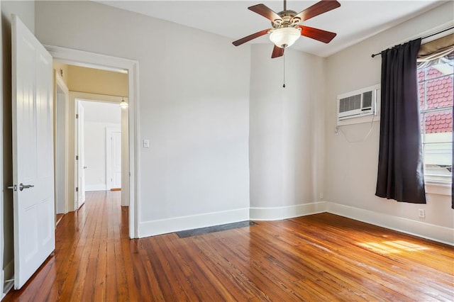 empty room with a wall mounted AC, hardwood / wood-style floors, and ceiling fan