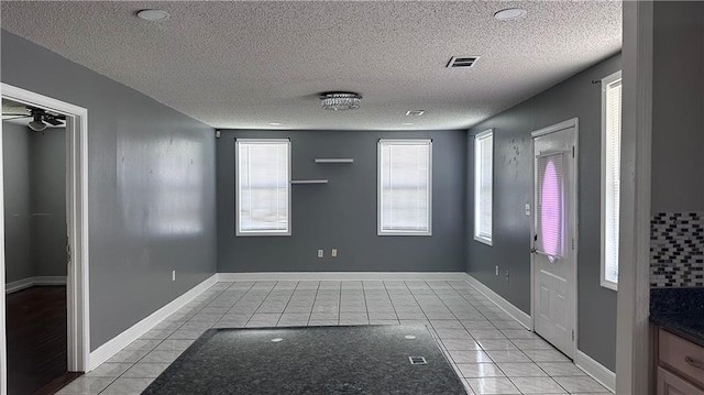 interior space featuring a textured ceiling, light tile patterned floors, and ceiling fan