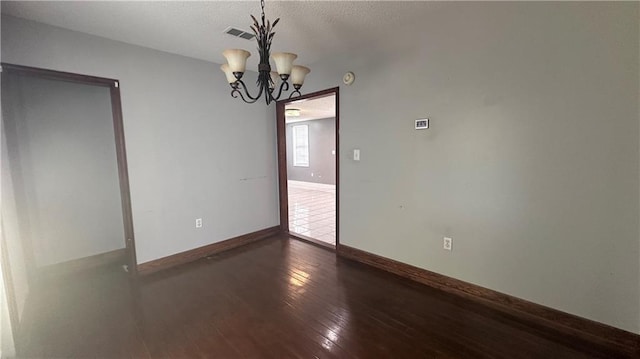 spare room featuring hardwood / wood-style flooring and a chandelier