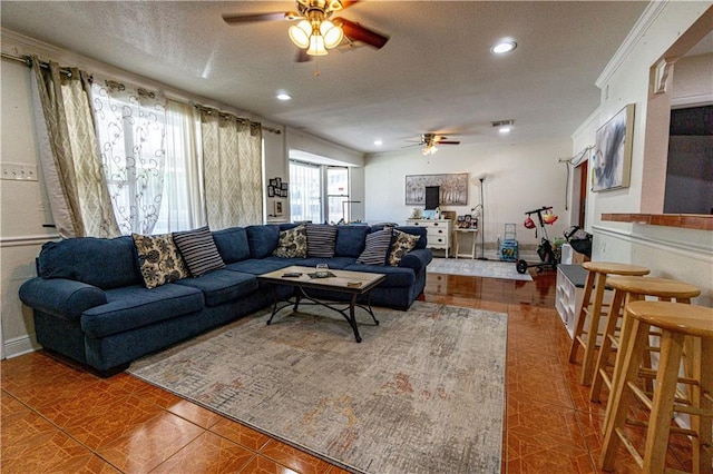 tiled living room with a textured ceiling, ornamental molding, and ceiling fan