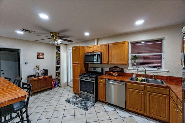 kitchen featuring appliances with stainless steel finishes, light tile patterned floors, ceiling fan, and sink