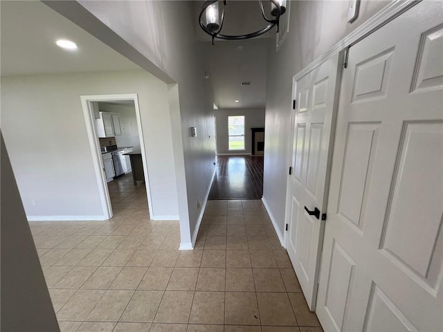 hall featuring a notable chandelier, light tile patterned floors, recessed lighting, and baseboards