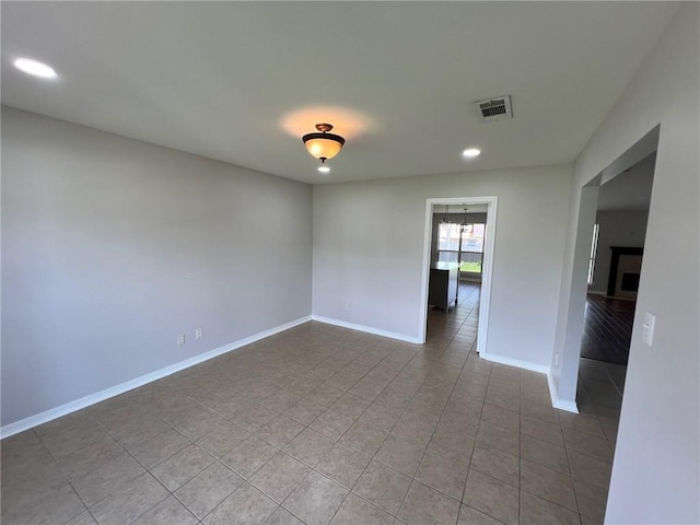 empty room featuring visible vents, baseboards, light tile patterned floors, recessed lighting, and a fireplace