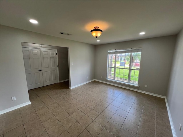 unfurnished bedroom featuring tile patterned flooring, visible vents, recessed lighting, and baseboards