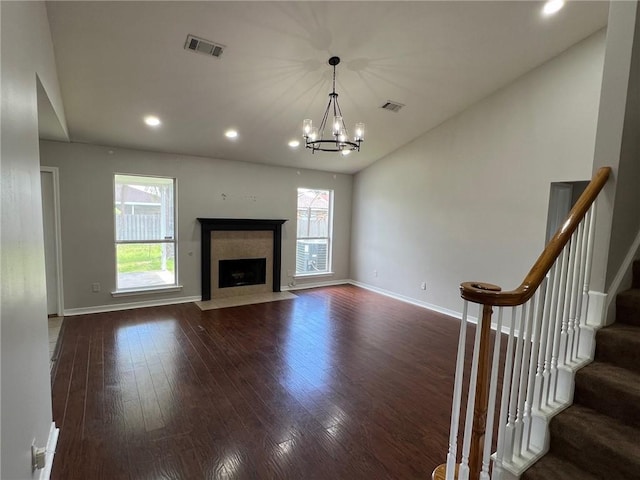 unfurnished living room with a high end fireplace, visible vents, plenty of natural light, and dark wood-style flooring