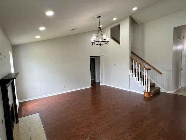 unfurnished living room with stairway, wood finished floors, an inviting chandelier, recessed lighting, and vaulted ceiling