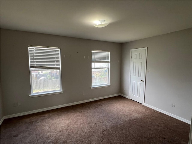 empty room with baseboards and dark carpet