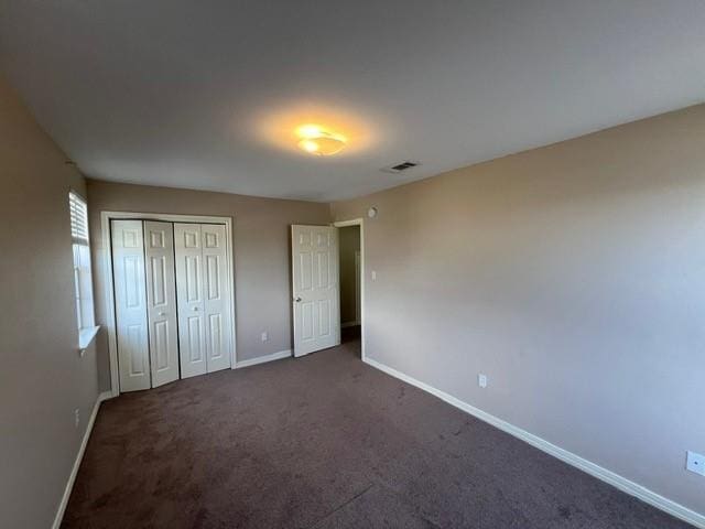 unfurnished bedroom with a closet, visible vents, baseboards, and carpet floors