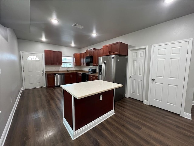 kitchen with sink, a center island, dark wood-type flooring, and stainless steel appliances