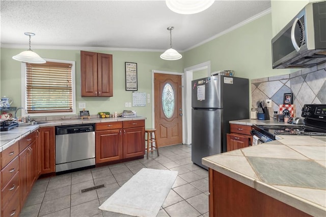 kitchen featuring crown molding, stainless steel appliances, decorative light fixtures, and backsplash