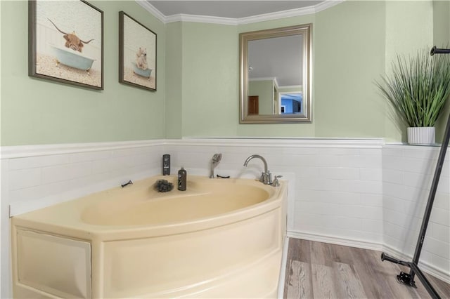 bathroom featuring hardwood / wood-style flooring, ornamental molding, and a bathing tub