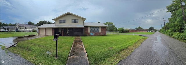 view of front of property with an attached garage, driveway, a front lawn, and metal roof