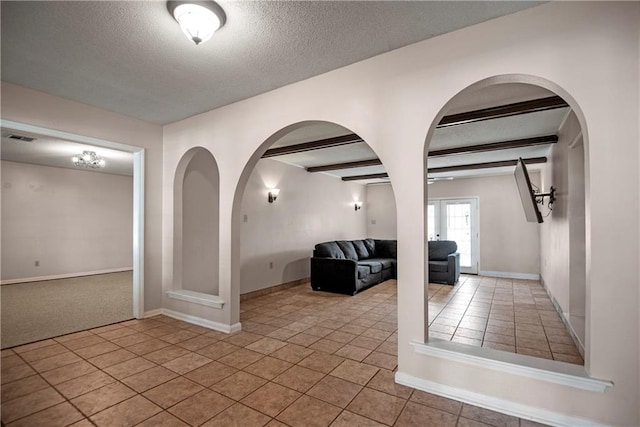 interior space featuring french doors, a textured ceiling, beamed ceiling, and light tile patterned flooring