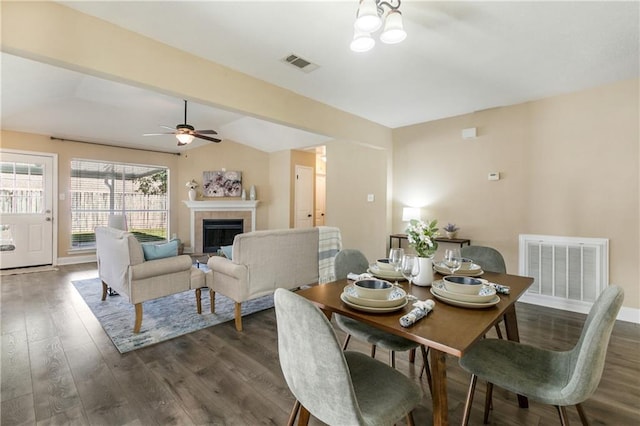 dining area featuring ceiling fan, dark hardwood / wood-style flooring, lofted ceiling, and a fireplace