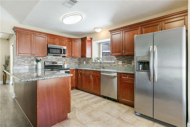 kitchen featuring decorative backsplash, light stone counters, sink, and stainless steel appliances