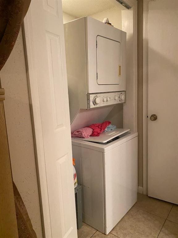 washroom with stacked washer and dryer and light tile patterned floors