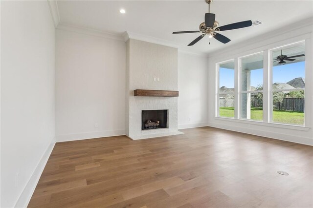 unfurnished living room featuring a brick fireplace, crown molding, and ceiling fan