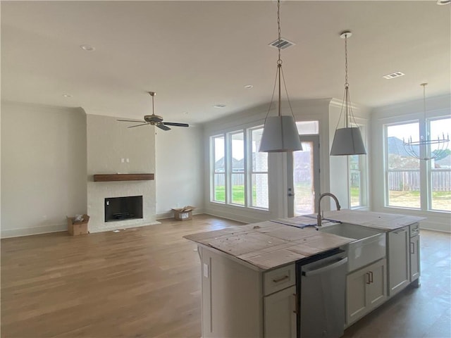 kitchen with a kitchen island with sink, pendant lighting, a wealth of natural light, and dishwasher