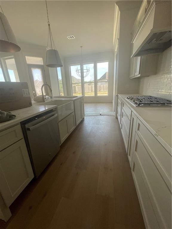 kitchen with appliances with stainless steel finishes, dark hardwood / wood-style floors, decorative light fixtures, white cabinets, and custom exhaust hood