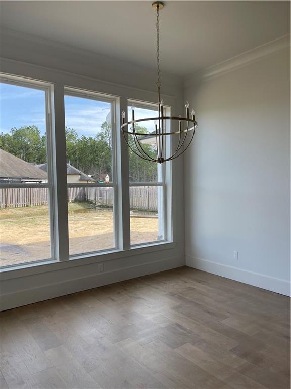 unfurnished dining area featuring an inviting chandelier, hardwood / wood-style floors, and a healthy amount of sunlight