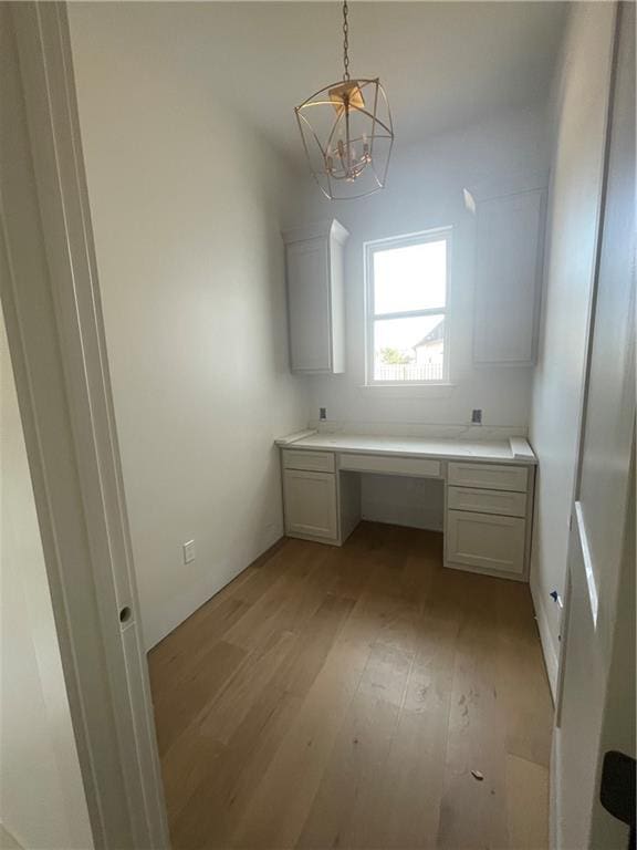 unfurnished office featuring built in desk and light wood-type flooring