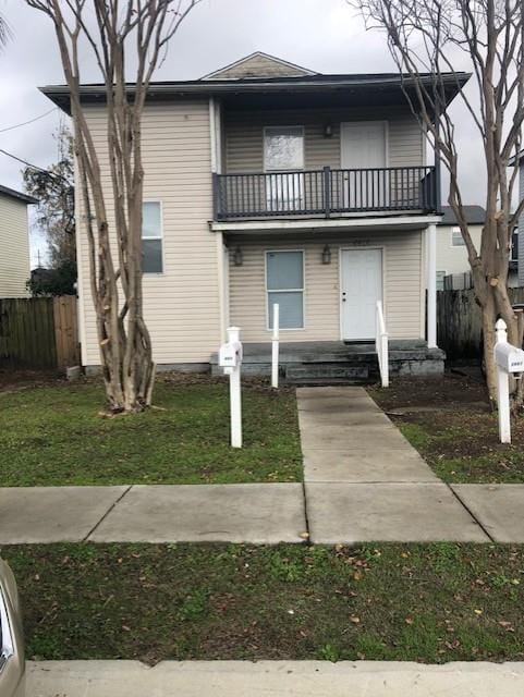 view of front of property with a balcony and a front lawn