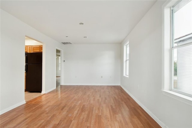 empty room with light hardwood / wood-style floors and a wealth of natural light