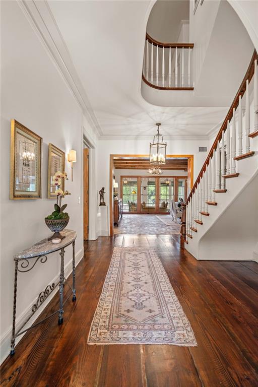 entrance foyer with dark hardwood / wood-style flooring, french doors, a notable chandelier, and ornamental molding