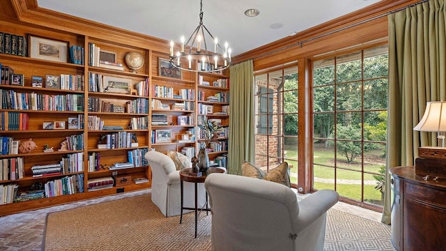 living area with built in shelves, an inviting chandelier, and crown molding