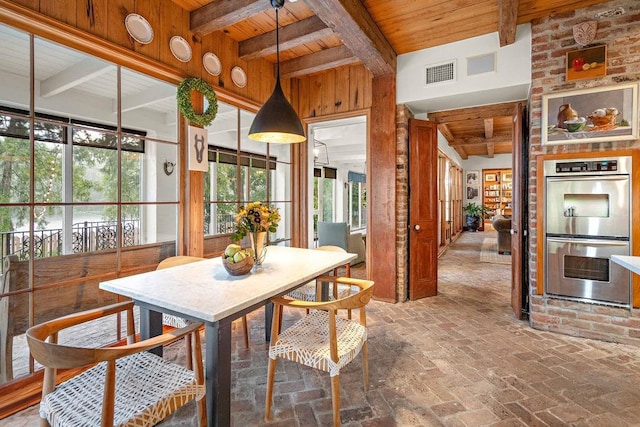 dining room featuring beamed ceiling, wood walls, and wood ceiling