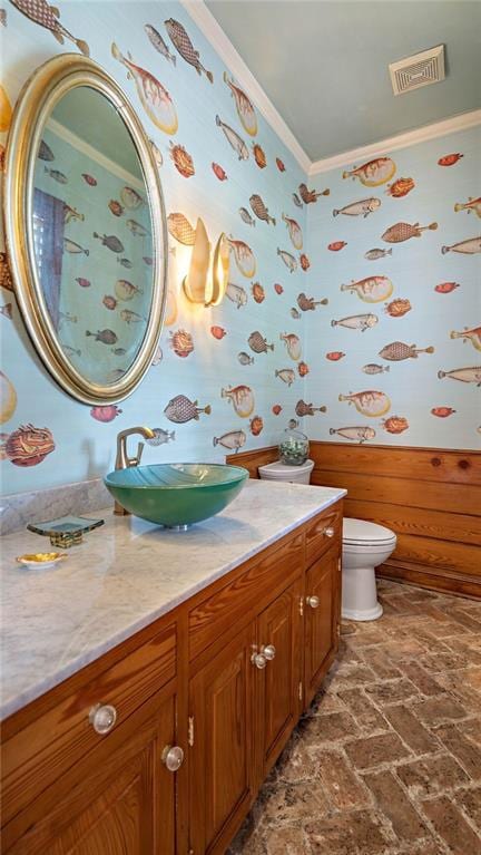 bathroom featuring toilet, vanity, and ornamental molding