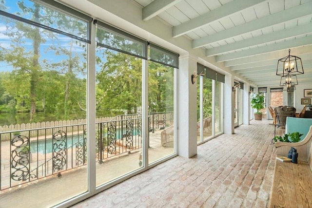 sunroom / solarium featuring a wealth of natural light, beamed ceiling, and an inviting chandelier