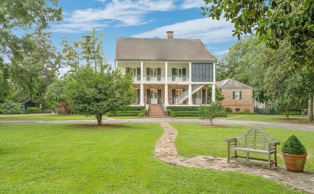 colonial inspired home featuring a porch, a balcony, and a front yard