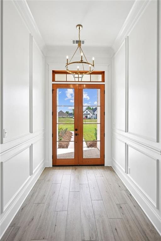 doorway featuring a chandelier, crown molding, french doors, and light hardwood / wood-style flooring