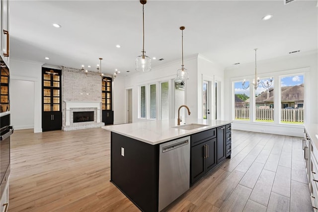 kitchen featuring dishwasher, light hardwood / wood-style floors, a brick fireplace, and sink