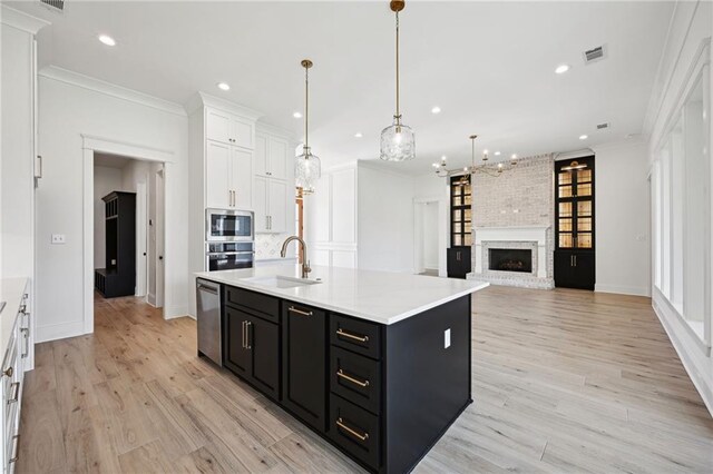 kitchen with crown molding, stainless steel appliances, light hardwood / wood-style floors, a brick fireplace, and sink