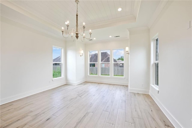 spare room featuring light wood-type flooring, a tray ceiling, and a notable chandelier