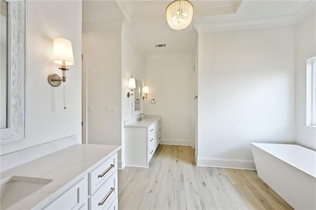 bathroom with wood-type flooring, a tub to relax in, vanity, and ornamental molding