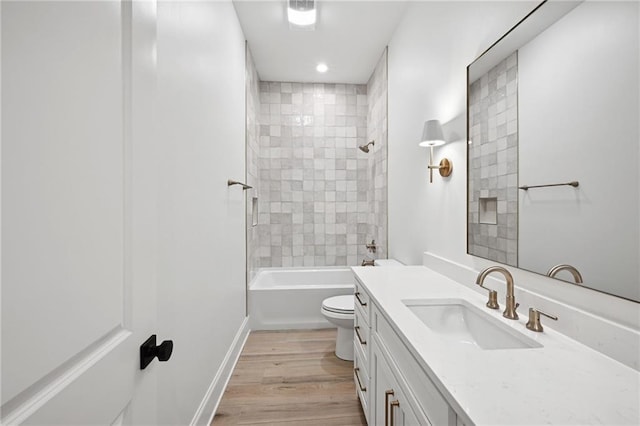 full bathroom with vanity, hardwood / wood-style flooring, tiled shower / bath, and toilet