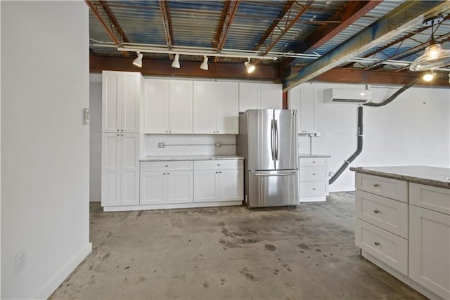 kitchen with a wall mounted AC, stainless steel refrigerator, and white cabinets