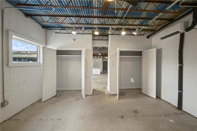 unfurnished bedroom with concrete flooring and an AC wall unit